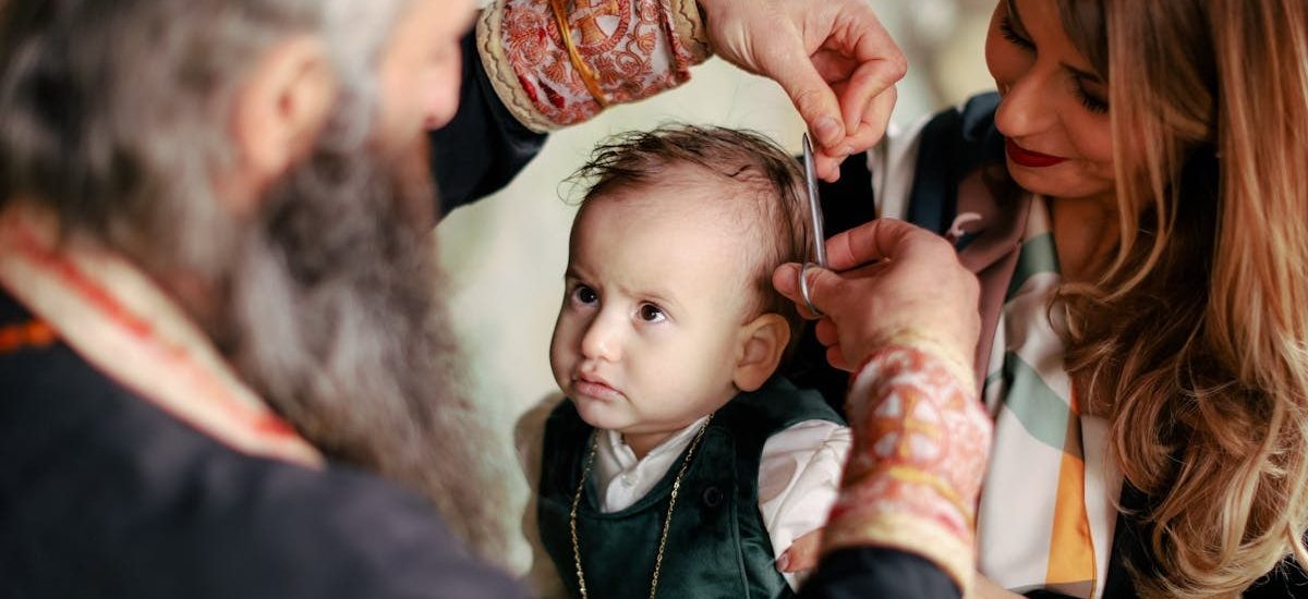 A baby's first haircut performed during a religious ritual with parents and clergy present.