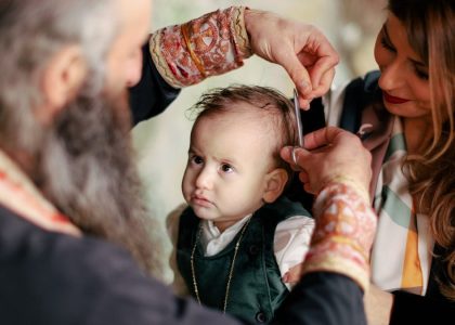 A baby's first haircut performed during a religious ritual with parents and clergy present.