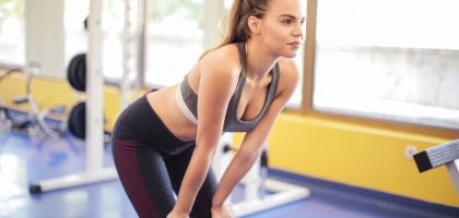 Fit woman performing a stretch indoors, showcasing fitness and active wear in a modern gym environment.